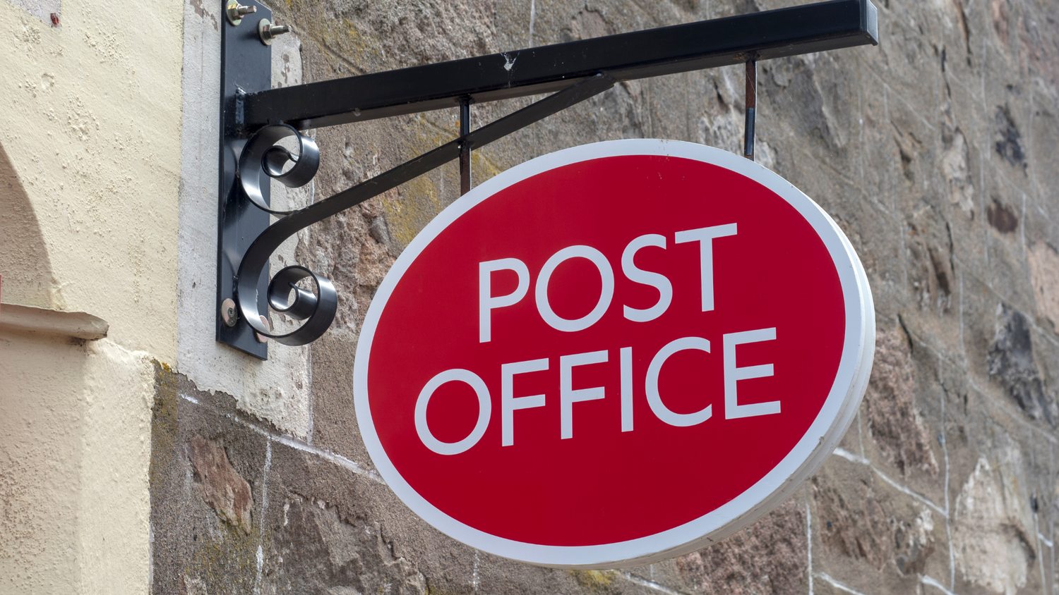 Red 'POST OFFICE' sign on a stone wall